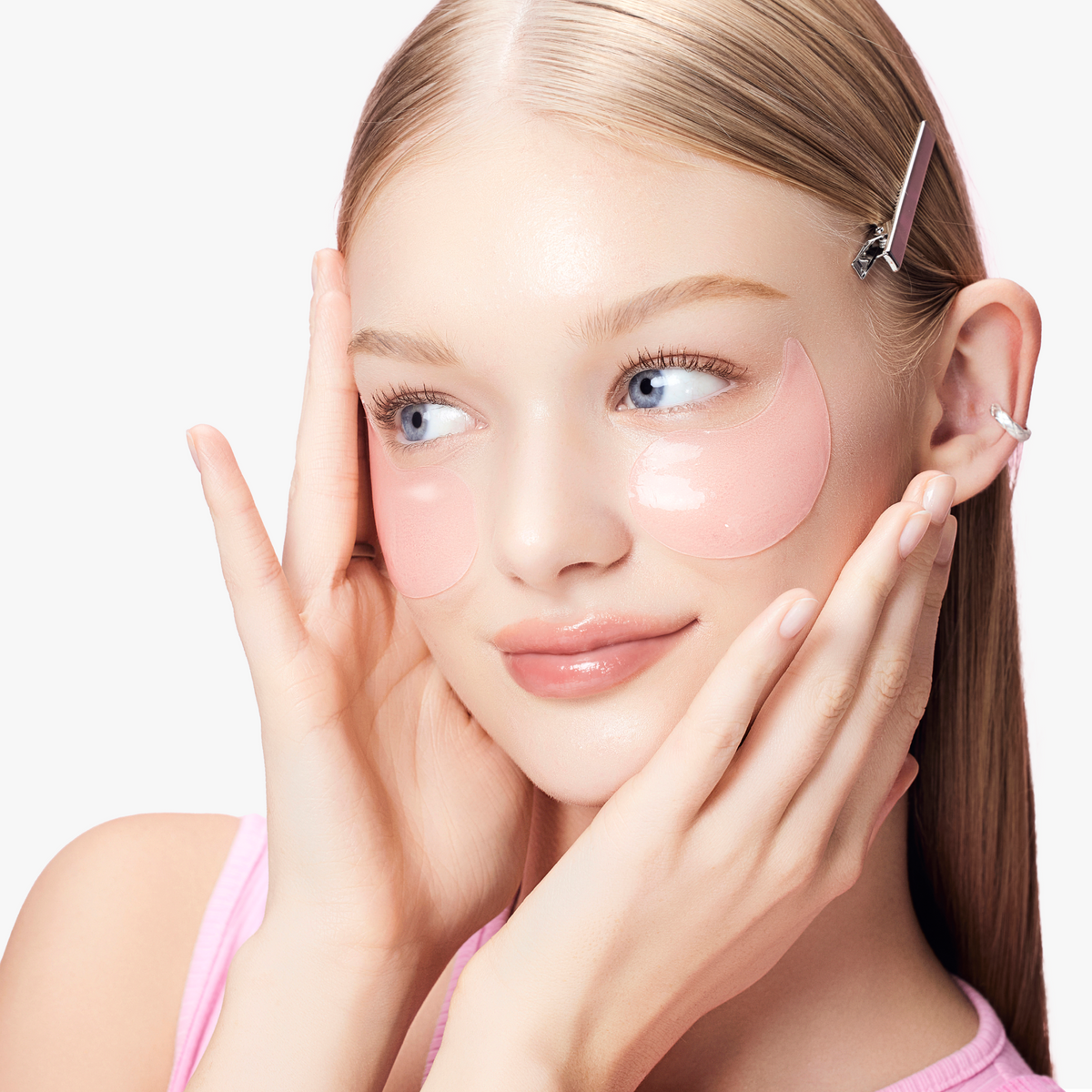 Close-up of blonde model wearing COSRX The Peptide Collagen Hydrogel Eye Patch under both eyes; soft pink hydrogel pads delivering targeted hydration and peptide-powered firming benefits to diminish the appearance of fine lines, puffiness, and dark circles for smooth, luminous skin.