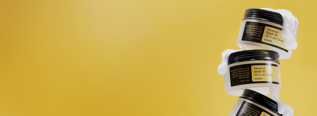 Stack of COSRX Advanced Snail 92 All In One Cream jars on yellow background with text ‘No.1 Global Cream’; daily recovery moisturizer formulated with 92% snail mucin to hydrate, repair barrier, and boost elasticity for luminous, glass-like skin. Global K-beauty favorite for anti-aging hydration care.