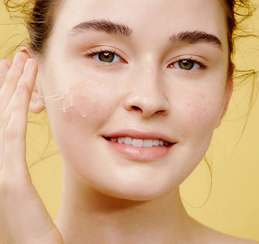 Model applying COSRX Advanced Snail 92 All In One Cream to cheek, showing natural glow and smooth hydration; Korean moisturizer with 92% snail mucin that calms irritation, evens tone, and delivers dewy, glass skin finish suitable for all skin types.